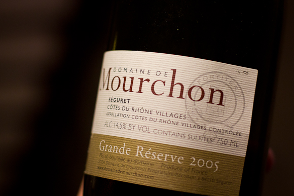 A closeup of the label of a bottle of Domaine de Mourchon. Relatively modern label design for a Cotes du Rhone, typographic emphasis