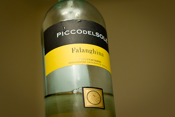 A bottle of Falanghina, an Italian white wine. Simple black and yellow label. The bottle, fresh from the fridge, is misted with condensation