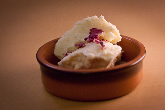 A small terracotta dish with ice cream, scattered with dried rose petals