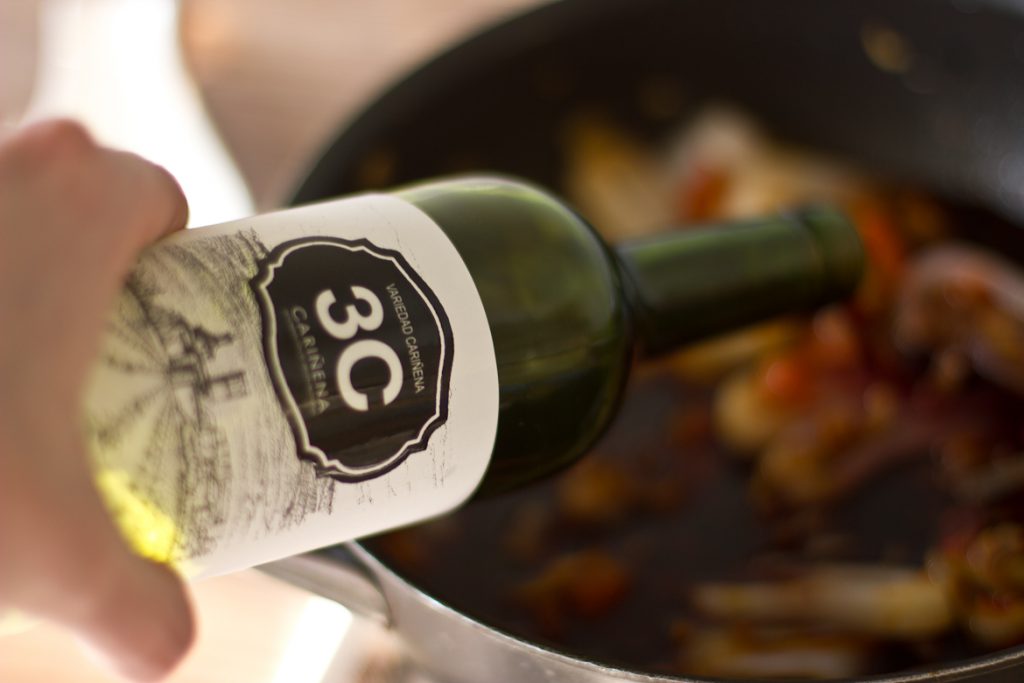 Bottle of 3C Carinena wine being poured into a stew for cooking