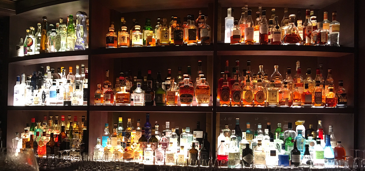 A huge selection of spirits lined up and beautifully lit in Hide Below bar in London