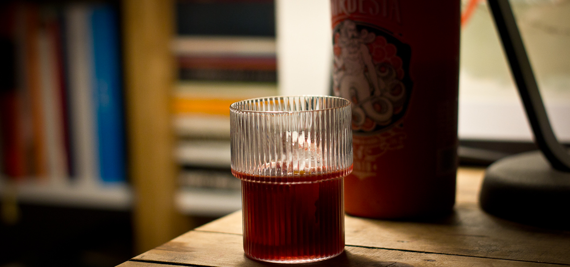 Glass of Nordesia Red Vermouth on ice, with bottle in the background