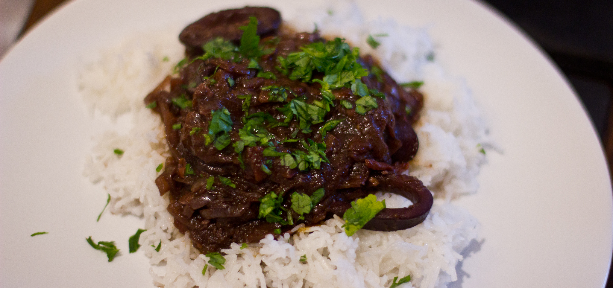 Dark squid stew on a plate with rice